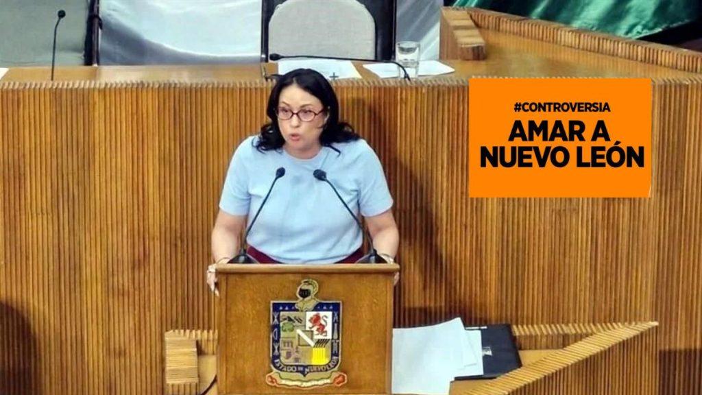 Woman Speaking from a Wooden Lectern in a Formal Chamber, with an Orange Sign Reading '#controversia Amar a Nuevo LeÓn' Nearby › La Sierra Madre
