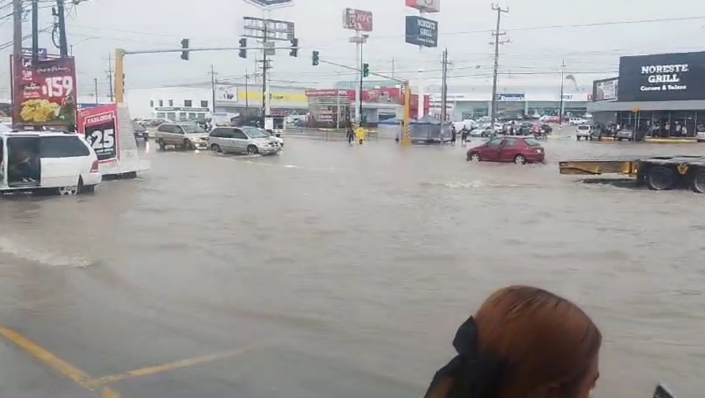 Street Intersection Heavily Flooded with Moving Cars and a Few Pedestrians; Storefronts Line the Background. › La Sierra Madre