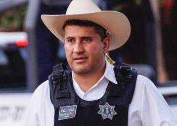 Municipal police officer wearing a bulletproof vest with a 'Policía Municipal' patch and a tan cowboy hat.