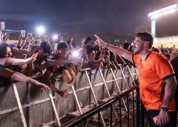 Man in an Orange Jersey High-fives Cheering Fans Behind a Barricade at Night › La Sierra Madre