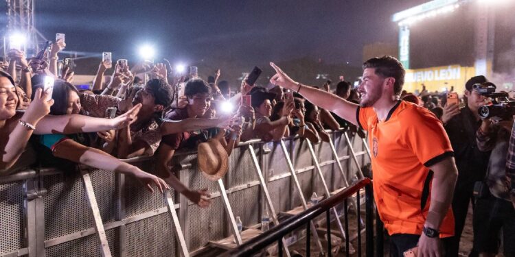 Samuel-garcia-fan-fest-parque › La Sierra Madre Man in an Orange Jersey High-fives Cheering Fans Behind a Barricade at Night › La Sierra Madre